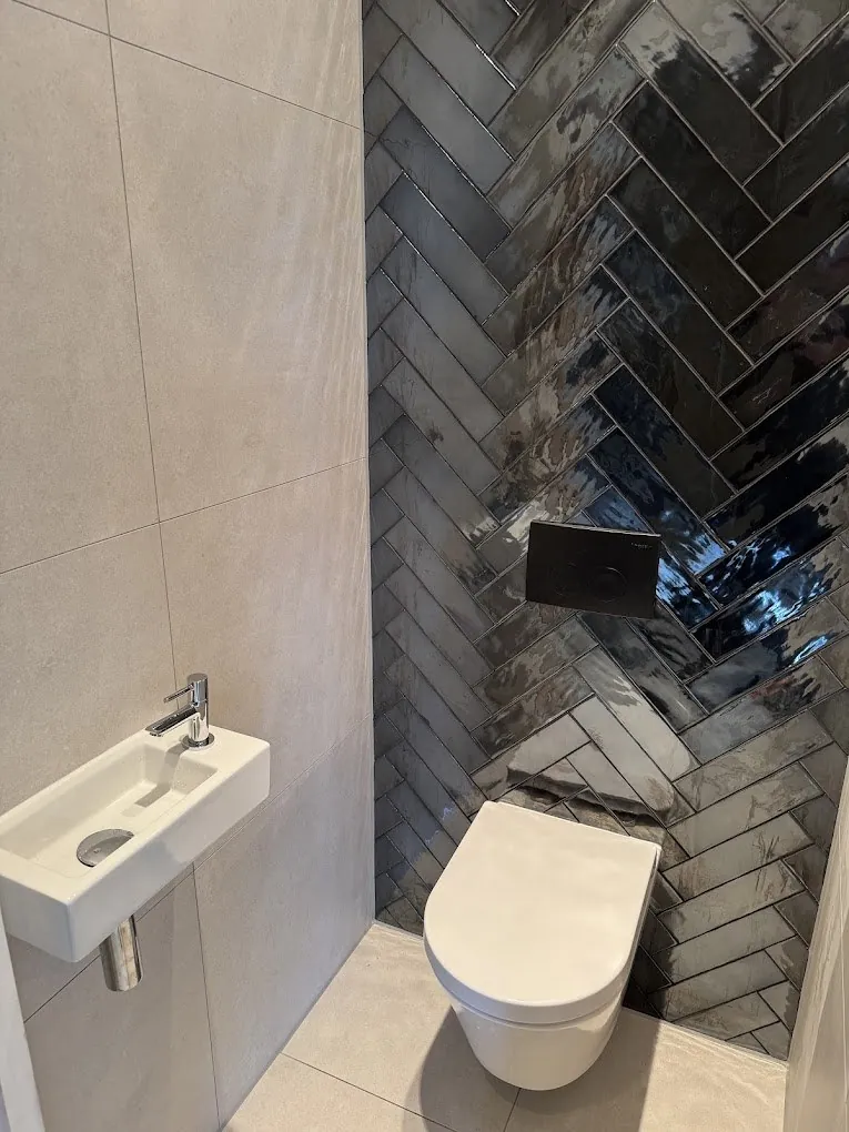 Vernieuwd toilet met fontein en tegelwand